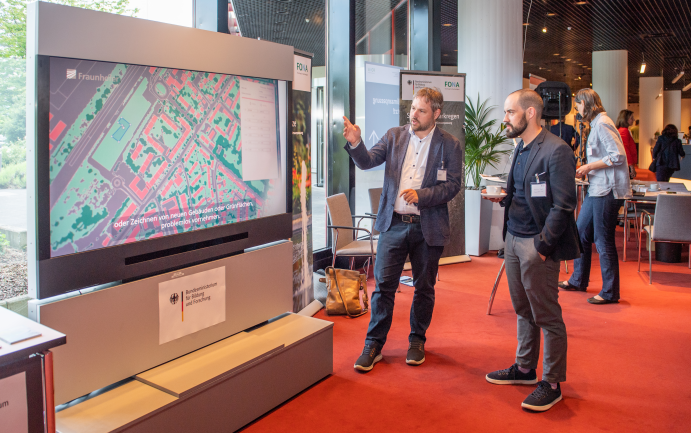 Matthias Winkler (Fraunhofer-Institut für Bauphysik IBP, Valley) erklärte am BMBF-Stand auf der 16. DStGB-Klimaschutzkonferenz die Möglichkeiten, die die Stadtklima-Simulationssoftware Kommunen bietet. 